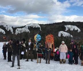 Crowd holding puppets on a snowy field and blue sky